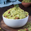 A bowl of green Kothmir Chiwda, which is a traditional Indian snack, consisting of crispy flattened rice and peanuts.